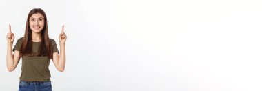 Gri arka planda yalnız duran mutlu ve şaşırmış genç bir bayan portresi. Kamera işaret ediyor