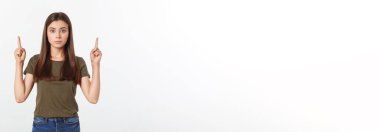 Gri arka planda yalnız duran mutlu ve şaşırmış genç bir bayan portresi. Kamera işaret ediyor