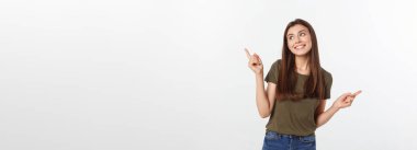 Gri arka planda yalnız duran mutlu ve şaşırmış genç bir bayan portresi. Kamera işaret ediyor