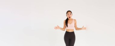 Şaşırmış ve şaşırmış kadın sporcu, etkin giyimli sporcu. Etkilenmiş görünüyor, çenesini indiriyor ve ellerini yana açıyor. İndirimli spor aletleri, indirimli spor aletleri..