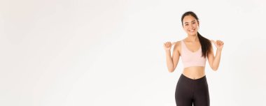 Spor, refah ve aktif yaşam tarzı konsepti. İnce ve güçlü gülümseyen, çekici Asyalı kadın fitness koçu, kişisel eğitmen ya da antrenör kendini gösteren spor salonu logonuz, beyaz arka plan..