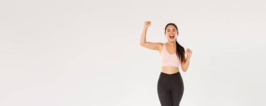 Motivasyonlu ve heyecanlı bayan sporcu, aktif giyimli Asyalı fitness kızı yumruk pompası ve bağırma cesaretlendirme, egzersiz hedefi kazanma, spor salonundaki verimli iyi eğitimle tatmin olma.