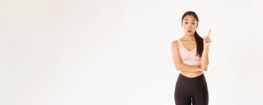 Spor, refah ve aktif yaşam tarzı konsepti. Düşünceli fit ve zayıf Asyalı kızın bir fikri var, sporcu kadın öneriler için işaret parmağını kaldır, egzersiz planı yap, beyaz arka planda dur.