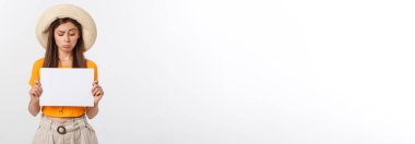 Kafkasyalı genç bir kadın, elinde boş bir kâğıt çarşaf ile izole edilmiş bir arkaplanı tutuyor. Şok olmuş, korkmuş ve heyecanlı bir yüz ifadesi var.