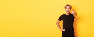 Sarı saçlı, neşeli ve yakışıklı Asyalı bir adamın portresi. Seni seçiyor, gülümsüyor ve kamerayı işaret ediyor. Tebrikler..