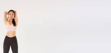 Tam boy odaklanmış ve motive olmuş Asyalı bayan sporcu, esmer fitness kızı esneme egzersizleri yaparken kararlı görünüyor, antrenmandan önce ısınma egzersizleri, el ele tutuşmalar....