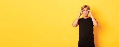 Sorunlu Asyalı erkek öğrencinin portresi. Baş ağrısı, ekşitme, baş ağrısı, migren ağrısı..