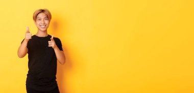 Yüzsüz, gülümseyen Asyalı adamın portresi, tatmin olmuş görünüyor ve kamerayı işaret ediyor, bir şeyi övüyor ya da iltifat ediyor..