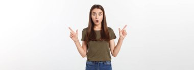 Gri arka planda yalnız duran mutlu ve şaşırmış genç bir bayan portresi. Kamera işaret ediyor