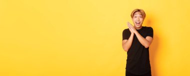 Mutlu ve şaşırmış Asyalı adamın portresi el çırpıyor ve gülümsüyor..