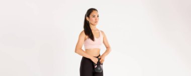 Spor, refah ve aktif yaşam tarzı konsepti. Yan bakış ciddi ve odaklanmış Asyalı güçlü fitness kızı, spor salonunda bayan sporcu, kettlebell egzersizi, ayakta duran beyaz arka plan.