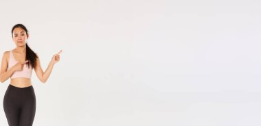 Şüpheci ve kuşkulu Asyalı kadın esmer, sporcu kızın şüpheleri var, sağ üst köşeyi işaret ediyor, kaşlarını çatıyor ve inançsızlıkla bakıyor, sportmen kadın reklamını yapıyor..