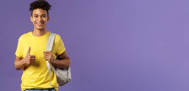 Okula dönmek, üniversite konsepti. Neşeli yakışıklı erkek öğrencinin portresi yaz tatilini sınıf arkadaşlarına tarif ediyor, tavsiye mektubu, onaylama, sırt çantası.