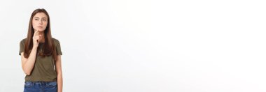 Gri arka planda yalnız duran mutlu ve şaşırmış genç bir bayan portresi. Kamera işaret ediyor