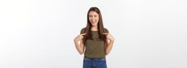 Gri arka planda yalnız duran mutlu ve şaşırmış genç bir bayan portresi. Kamera işaret ediyor