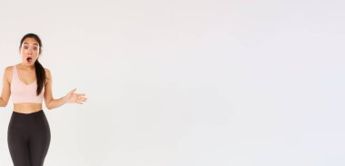 Şaşırmış ve şaşırmış kadın sporcu, etkin giyimli sporcu. Etkilenmiş görünüyor, çenesini indiriyor ve ellerini yana açıyor. İndirimli spor aletleri, indirimli spor aletleri..