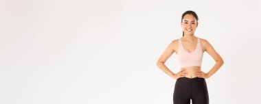 Spor, refah ve aktif yaşam tarzı konsepti. Aktif giyimli kadın portresi beyaz arka planda kendinden emin duruyor. Kadın sporcu, fitness koçu neşeli görünüyor, antrenmana başlıyor..