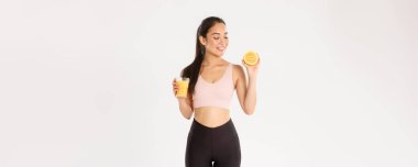 Spor, refah ve aktif yaşam tarzı konsepti. Sağlıklı ve ince Asyalı kız tavsiyelerinin portresi kahvaltıda sağlıklı yiyecekler yemek, egzersiz için enerji kazanmak, taze meyve suyu ve portakal suyu içmek..