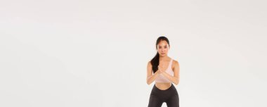 Tam boy iyi görünümlü bayan sporcu, Asyalı fitness kızı sıkı sıkıya bağlı ellerle çömelme hareketleri ve uyluklara direnç bandı uygulayarak, antrenman sırasında egzersiz ekipmanları kullanarak,.
