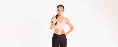 Spor, refah ve aktif yaşam tarzı konsepti. Ciddi ve hoşnutsuz Asyalı sporcu kadın dur jesti, kadın fitness koçu ya da eğitmen uyarısı, kısıtlı spor salonu müşterisi, beyaz arka plan.