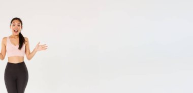 Şaşırmış ve şaşırmış kadın sporcu, spor ayakkabılı ve tozlu Asyalı sporcu kız merak ediyor, heyecanla gülüyor ve yan yana uzanıyor, özel spor salonu indirimlerini öğrenin..