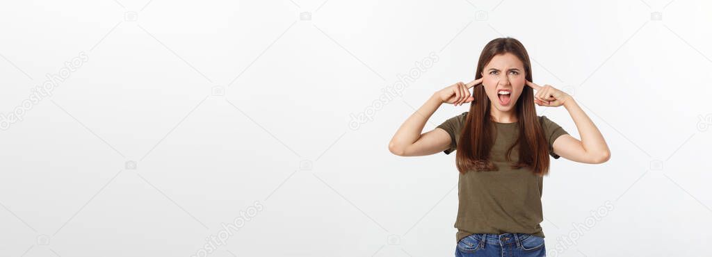 Closeup portrait of a young angry woman covering her ears, stop making that loud noise its giving me a headache, isolated on white background