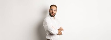 Kafası karışmış yönetici kameraya bakıyor, beyaz arkaplana karşı şokta..