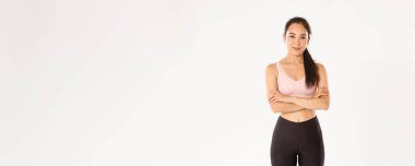 Spor, refah ve aktif yaşam tarzı konsepti. Kendinden emin ve motive Asyalı sporcu kadın antremana hazır, kollarını kavuşturup gülümsüyor ve verimli bir eğitim için cesaretlendiriliyor..