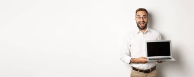 İşadamı dizüstü bilgisayar ekranı gösteriyor, heyecanlı görünüyor, beyaz arka planda duruyor..