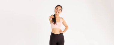 Spor, refah ve aktif yaşam tarzı konsepti. Neşeli ve şevkli Asyalı kadın fitness müfettişinin portresi, spor salonuna davet edilen spor salonu üyesi, kameraya işaret eden ve gülümseyen..