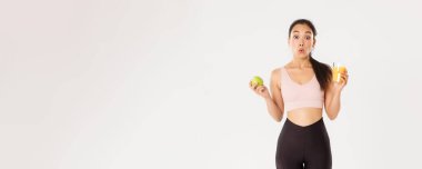 Spor, refah ve aktif yaşam tarzı konsepti. Hoş Asyalı kız spor yapmayı ve sağlıklı yiyecekler yemeyi seviyor. Elma ve portakal suyu tutuyor. 