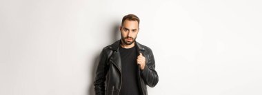 Yakışıklı, sakallı, kendine güvenen, deri ceketine dokunan, kendine güvenen, beyaz bir geçmişi olan bir adam..