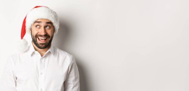 Noel Baba şapkalı mutlu sakallı adamın yakın çekimi Noel 'i ve yeni yılı kutluyor ve sol üst köşeye bakıyor, bir şeyler hayal ediyor. beyaz arkaplan.