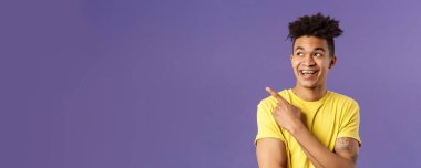 Korkulu komik İspanyol bir adamın yakın plan portresi, bir şeye gülüyor ve gülümsüyor, sol üst köşedeki coşkulu ifadeye bakıyor, mor arka plan..