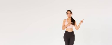 Şüpheci ve kuşkulu Asyalı kadın esmer, sporcu kızın şüpheleri var, sağ üst köşeyi işaret ediyor, kaşlarını çatıyor ve inançsızlıkla bakıyor, sportmen kadın reklamını yapıyor..