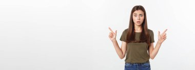 Gri arka planda yalnız duran mutlu ve şaşırmış genç bir bayan portresi. Kamera işaret ediyor
