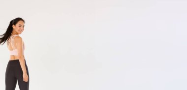 Aktif ve sağlıklı Asyalı fitness kızı, sporcu kadın kameraya tatmin olmuş bir şekilde bakıyor, beden eğitimi koçu antrenmanlara başlıyor, beyaz arka plan..