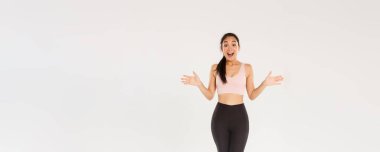 Şaşırmış ve şaşırmış kadın sporcu, spor ayakkabılı ve tozlu Asyalı sporcu kız merak ediyor, heyecanla gülüyor ve yan yana uzanıyor, özel spor salonu indirimlerini öğrenin..