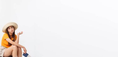 Yaşam tarzı ve seyahat kavramı: genç güzel beyaz kadın suitecase üzerinde oturan ve onu uçuş için bekliyor. Beyaz arka plan üzerinde izole.