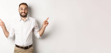 Kararsız işadamı iki varyantı gösteriyor, seçim yapmakta zorlanıyor, beyaz arka planda duruyor..