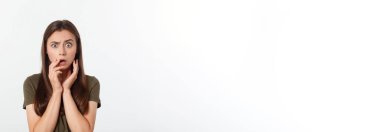 Şaşırmış ve ağzı açık bir şekilde kafasını tutan güzel bir kızın yakın plan portresi. Beyaz arkaplan.