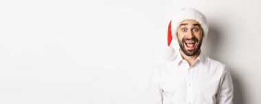 Noel Baba şapkalı mutlu sakallı adamın yakın çekimi, şaşırmış görünüyor, Noel 'i kutluyor, beyaz arka planda duruyor..