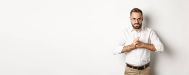 Kızgın adam parmak eklemlerini kırıyor, birini yumruklamak istiyor, beyaz arka plana karşı kızgın duruyor..