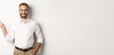 Kendine güvenen işadamı, beyaz arka planda duran şirket logosunu işaret ediyor..