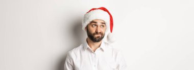 Noel Baba şapkalı şüpheci adamın yakın çekimi solda şüpheli görünüyor, tereddüt içinde, beyaz bir geçmişi var..