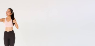 Tam boy gülümseyen kadın yaşam tarzı blogcusu, spor giyim sektöründe Asyalı fitness kızı selfie çekiyor, baş parmaklarını kaldırıyor, online takipçiler için egzersiz egzersizleri yapıyor, antrenmanlardan canlı yayın yapıyor..