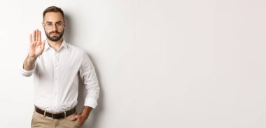 Gözlüklü ciddi bir patron dur işareti gösteriyor, hayır diyor, yasaklıyor, beyaz arka planda duruyor..