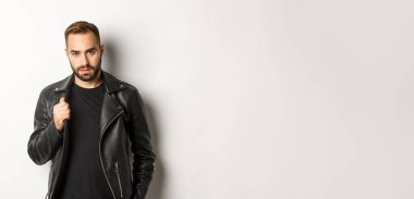 Yakışıklı, sakallı, kendine güvenen, deri ceketine dokunan, kendine güvenen, beyaz bir geçmişi olan bir adam..