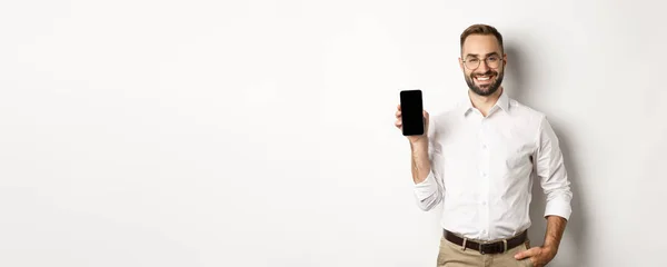 Zufriedener Geschäftsmann Zeigt Handybildschirm Lächelt Stolz Steht Über Weißem Hintergrund — Stockfoto