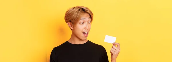 Närbild Förvånad Asiatisk Kille Talar Kreditkort Står Över Gul Bakgrund — Stockfoto